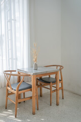 Fototapeta na wymiar Classic set of wooden chairs and table with light shines through the translucent curtains on the windows for modern house and decoration living room.