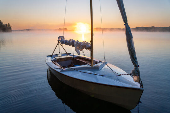 Dinghy Sailboat on Misty Lake At Sunrise