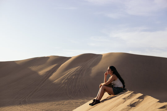 Woman Sitting In Sandy Dunes In Desert