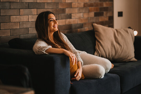 Smiling woman watching entertaining series on sofa