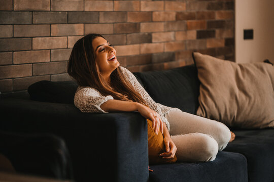Joyful woman watching entertaining show on sofa