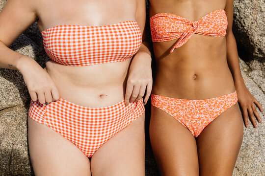 two women of different size and race wearing bikinis