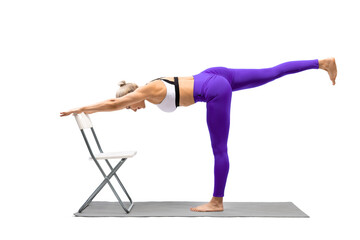 Iyengar yoga balance. Fit caucasian woman in purple leggings practice warrior pose III using a...