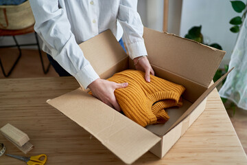 Woman putting sweater in carton box