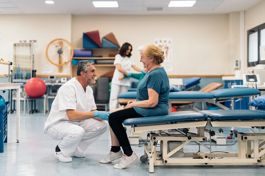 Happy male osteopath speaking with senior patient