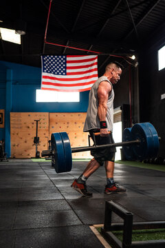 Strong man with heavy barbells in gym