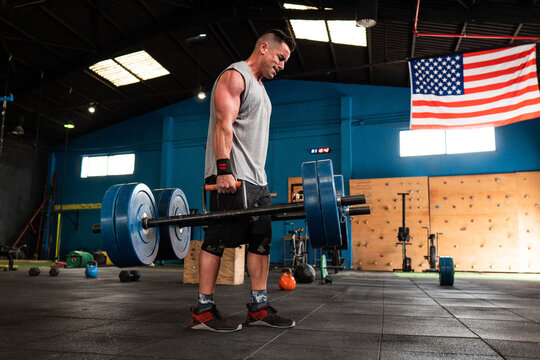 Strong man with heavy barbells in gym