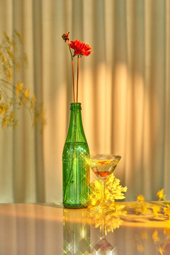 Natural sunlight on a bottle with flowers and a wine glass