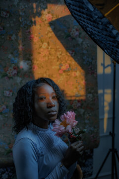 portrait of a curly-haired woman with a flower at home at sunset