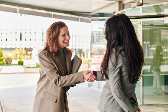 Businesswomen shaking hands at an office entrance
