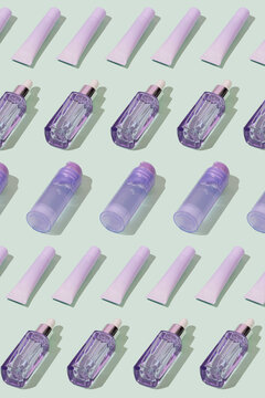 Pattern made of purple cosmetics against a mint green background.