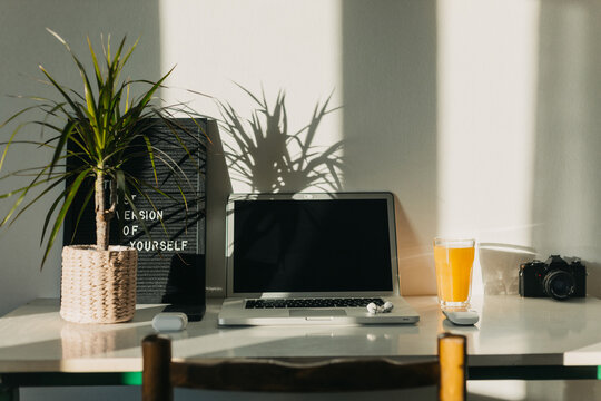 Laptop And Glass With Juice On White Desk. 