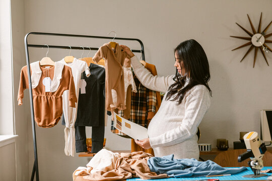 Pregnant business owner reviewing clothes design