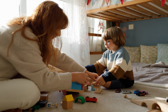 A boy and his mom are playing with toys at home