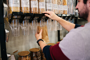 Man packing organic cereal  in eco friendly grocery shop