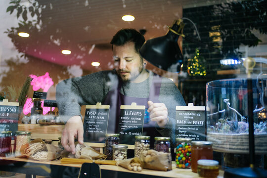 Male seller arranging sweets behind shop window