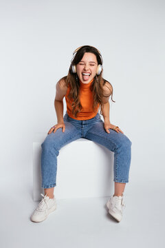 Joyful teenage lady in headphones showing tongue
