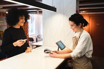 Woman paying drinks with mobile phone