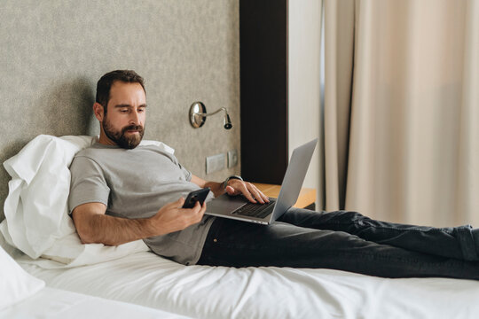 Bearded man checking notifications and using laptop