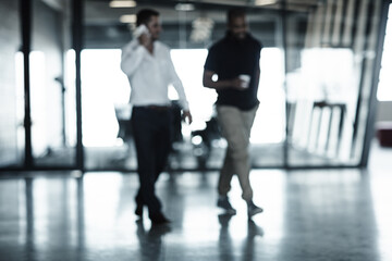Wrapping up a call on the way to lunch. Full length shot of two businessmen walking through an office.