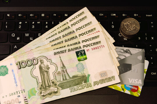 Russian paper money bank cards and a stack of coins on a computer keyboard