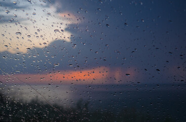 Drops of clean water on the surface of a car window. Water beading after rain with seascape background. Water drop background.