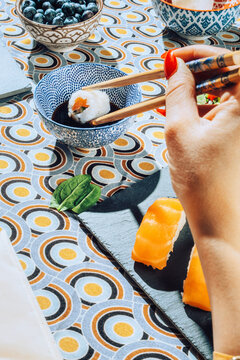 Female hands driping sushi in soya sauce.