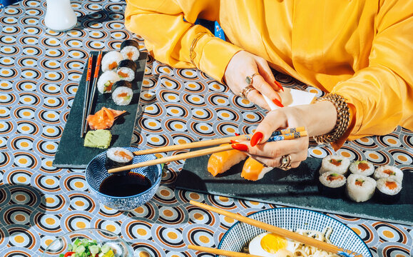 Stylish female eating with chopsticks japanese sushi roll.