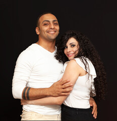 Portrait of a young couple in white t-shirts on a black background. High quality photo