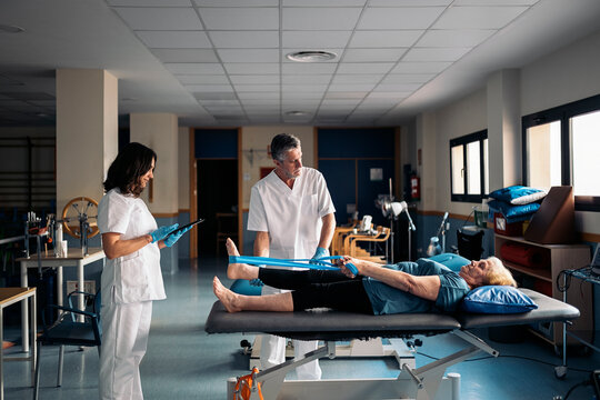Physiotherapists stretching leg of woman
