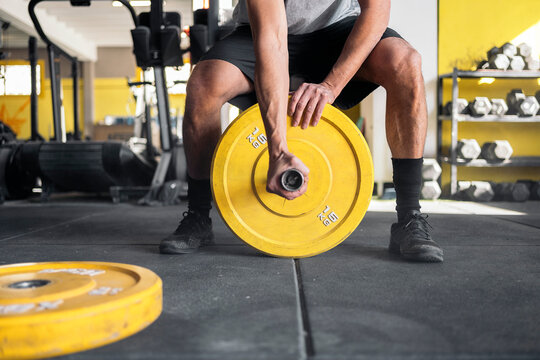 Crop athlete preparing barbell for training