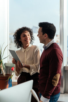 Cheerful couple using tablet in office near window at sunset