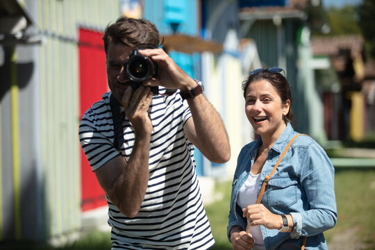 man snaps a photograph while cheerful girlfriend watches