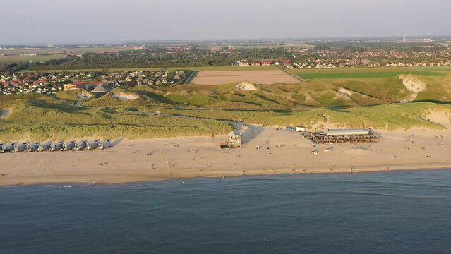 Drohnenaufnahme, Drohnenflug direkt &uuml;ber den Strand, die Nordseek&uuml;ste und die Roompot Ferienh&auml;user Strandh&auml;user, Im Hintergrund die Nordsee D&uuml;nen bei Julianadorp, Nordholland, Den Helder, Niederlande