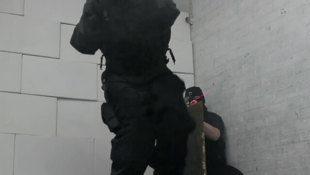 Armed special forces in gas masks and balaclavas enter building through hatch in floor through a tunnel