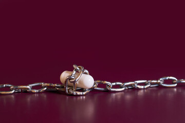 Drug addiction. White capsule rewound by a chain 