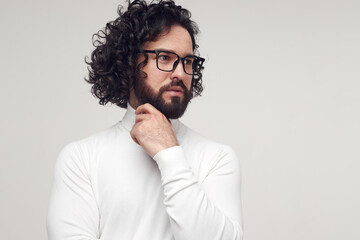 Obraz premium Pensive bearded man in eyeglasses touching chin in studio