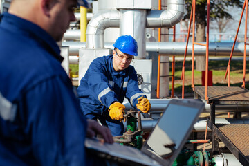 Worker adjusting gauge at oil refinery