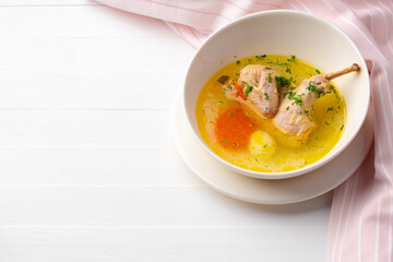 Chicken soup with vegetables in white bowl on wooden table