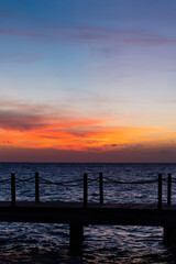 Obraz premium Rope bridge silhouette at sunset. Beautiful seascape, bright orange sky and sea