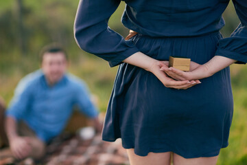 Shes plucked up the courage to pop the question instead. Rear view shot of a woman about to propose to her boyfriend with an engagement ring in a box.