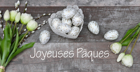 Carte de Pâques : Oeufs de Pâques et fleurs avec le texte Joyeuses Pâques sur le vieux bois.