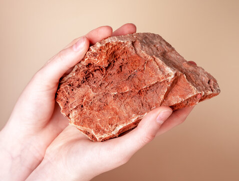 Woman hands holding red stone. Tactile sense and taction concept. Naturalness. Fingertips receptors contacting solid natural object and receiving information about world. High quality photo