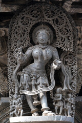 Fototapeta na wymiar Stone Sculpture of Beautiful Female (Madanikas) with selective focus, 12th century Hindu temple, Ancient stone art and sculptures in each pillars, Chennakeshava Temple, Belur, Karnataka, India.