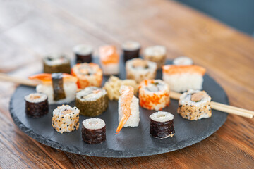 Stone plate with sushi on wooden table