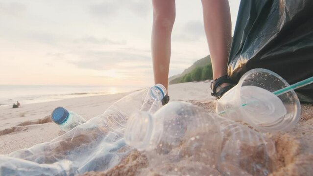 Volunteer woman hands lifting plastic garbage from sand for disposal of non-decomposable trash fighting climate change saving ocean and ecology of pollution. Concept cleaning beach after rest.