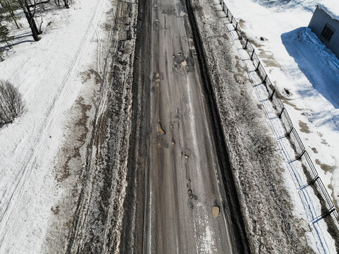 Broken old asphalt road outside the city. Pits and potholes. Aerial view