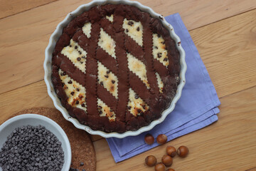 Chocolate shortcrust pastry filled with ricotta cheese and chocolate pieces on wooden table