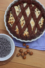 Chocolate shortcrust pastry filled with ricotta cheese and chocolate pieces on wooden table