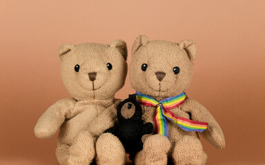 Gay couple bear toys and baby bear sitting against brown background